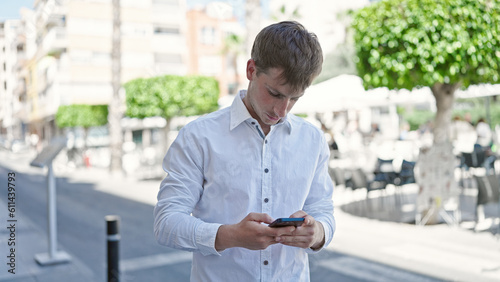 Young caucasian man using smartphone with serious expression at coffee shop terrace