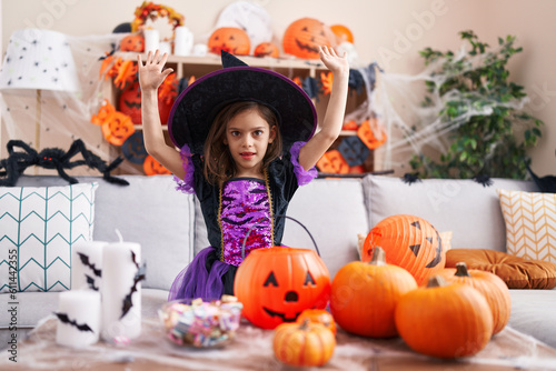 Adorable hispanic girl having halloween party with winner expression at home