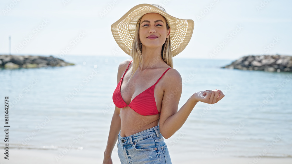Young blonde woman tourist smiling confident wearing bikini and summer hat at beach