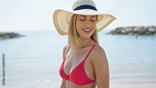 Young blonde woman tourist smiling confident wearing bikini and summer hat at beach © Krakenimages.com