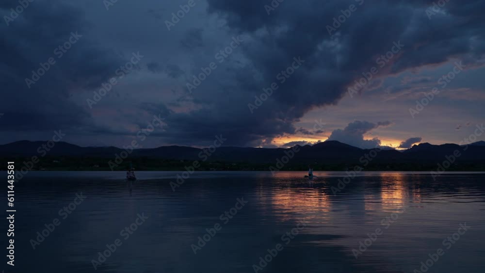 dramatic sunset sky and clouds over Rocky Mountains and lake in northern Colorado with a couple of distant paddlers dramatic sunset sky and clouds over Rocky Mountains and lake in northern Colorado with a couple of distant paddlers