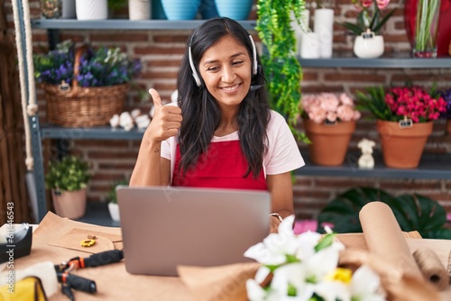 Young hispanic woman working at florist shop doing video call smiling happy and positive, thumb up doing excellent and approval sign © Krakenimages.com