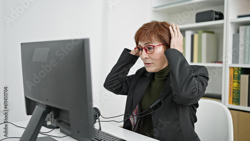 Mature hispanic woman university teacher putting headset on at library university