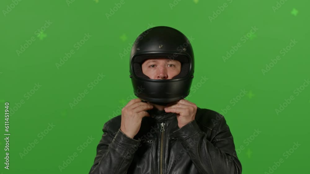 Close-up of Man Wears black full Face Motorcycle Helmet Before Riding a Bike. on green screen chroma key background. People, modern lifestyle and youth concept. Close-up of Man Wears black full Face Motorcycle Helmet Before Riding a Bike. on green screen chroma key background. People, modern lifestyle and youth concept.