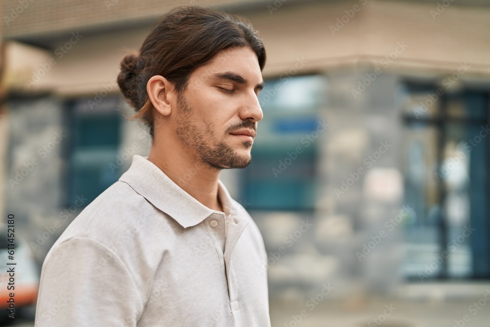 Young hispanic man standing with relaxed expression and close eyes at street