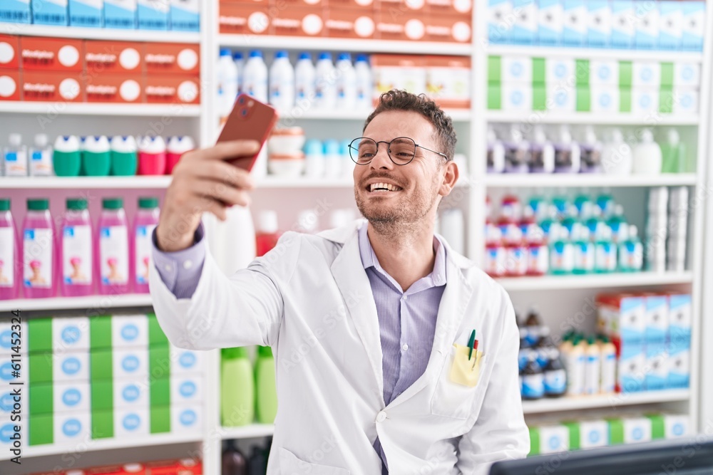 Young hispanic man pharmacist smiling confident make selfie by smartphone at pharmacy