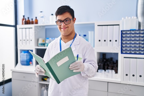 Down syndrome man wearing scientist uniform reading notebook at laboratory