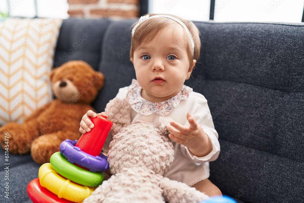 Adorable caucasian baby playing with hoops game sitting on sofa at home Adorable caucasian baby playing with hoops game sitting on sofa at home