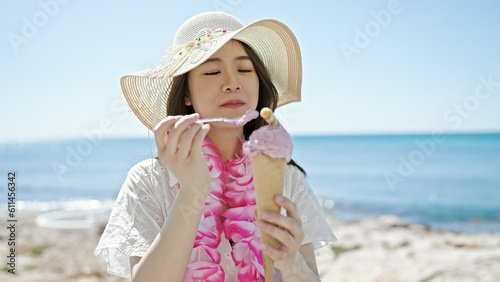 Fotografie Young chinese woman tourist eating ice cream at seaside