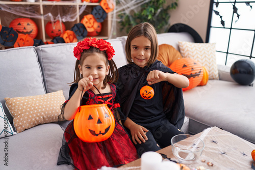 Adorable boy and girl having halloween party holding pumpkin basket at home