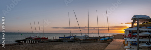SOUTHEND-ON-SEA, ESSEX, UK - SEPTEMBER 10, 2009: Panorama view of dinghies and sailboards on a jetty at Thorpe Esplanade with a setting sun and Southend Pier in the background