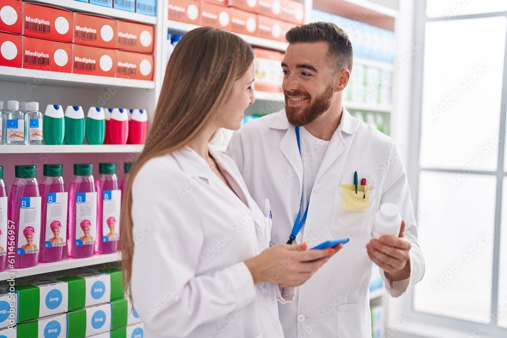 Man and woman pharmacists using touchpad holding pills bottle at pharmacy Man and woman pharmacists using touchpad holding pills bottle at pharmacy