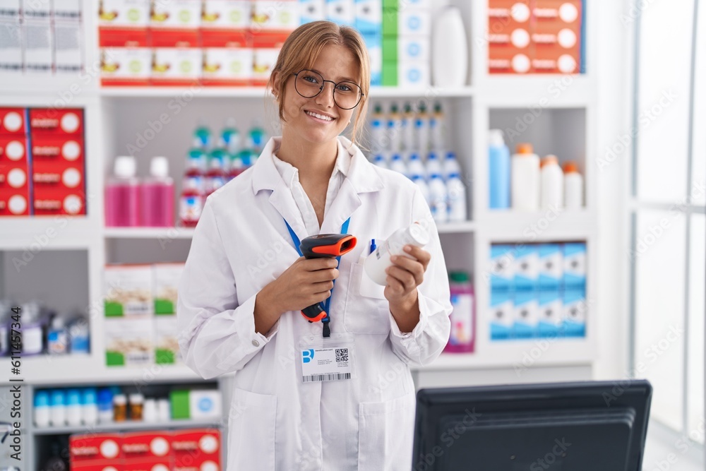 Young blonde girl pharmacist scanning pills bottle at pharmacy Young blonde girl pharmacist scanning pills bottle at pharmacy