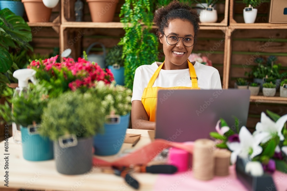 African american woman florist smiling confident using laptop at flower shop