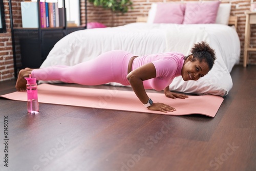 African american woman smiling confident training push up at bedroom