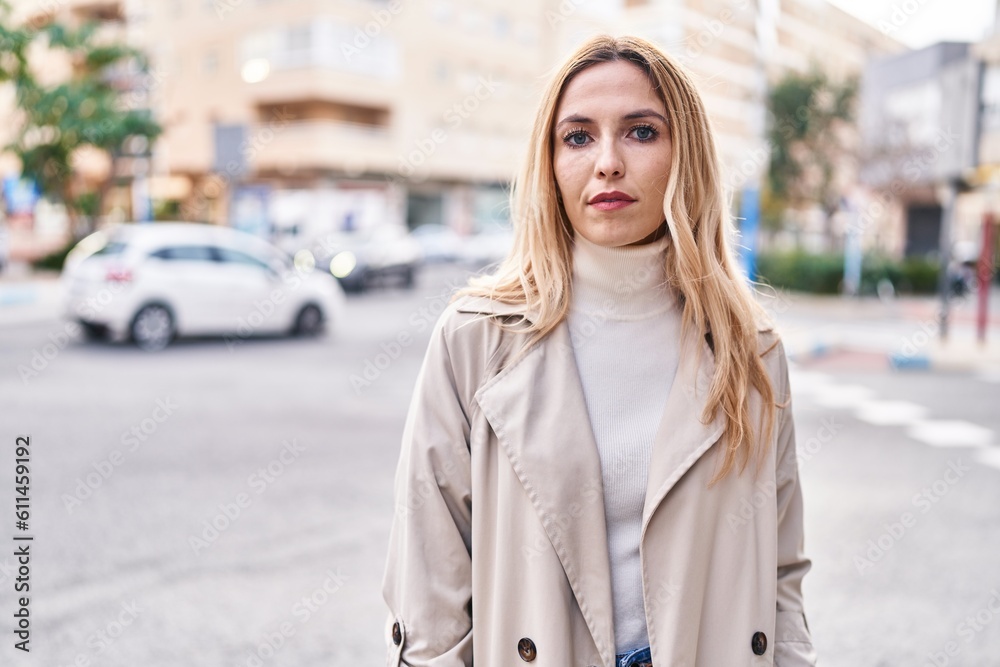 Fototapeta premium Young blonde woman standing with serious expression at street