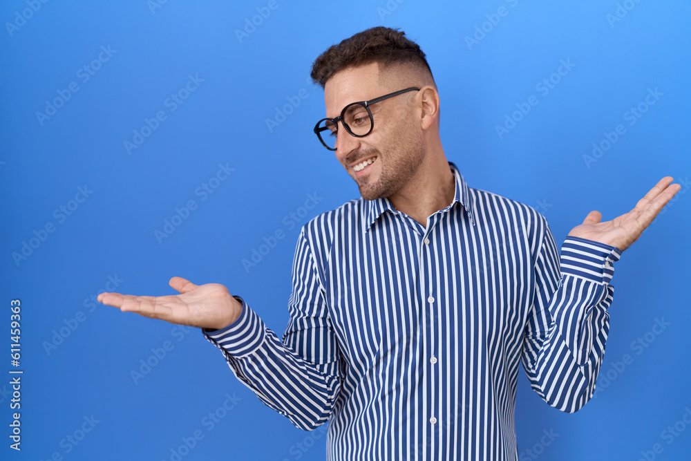 Hispanic man with beard wearing glasses smiling showing both hands open palms, presenting and advertising comparison and balance Hispanic man with beard wearing glasses smiling showing both hands open palms, presenting and advertising comparison and balance