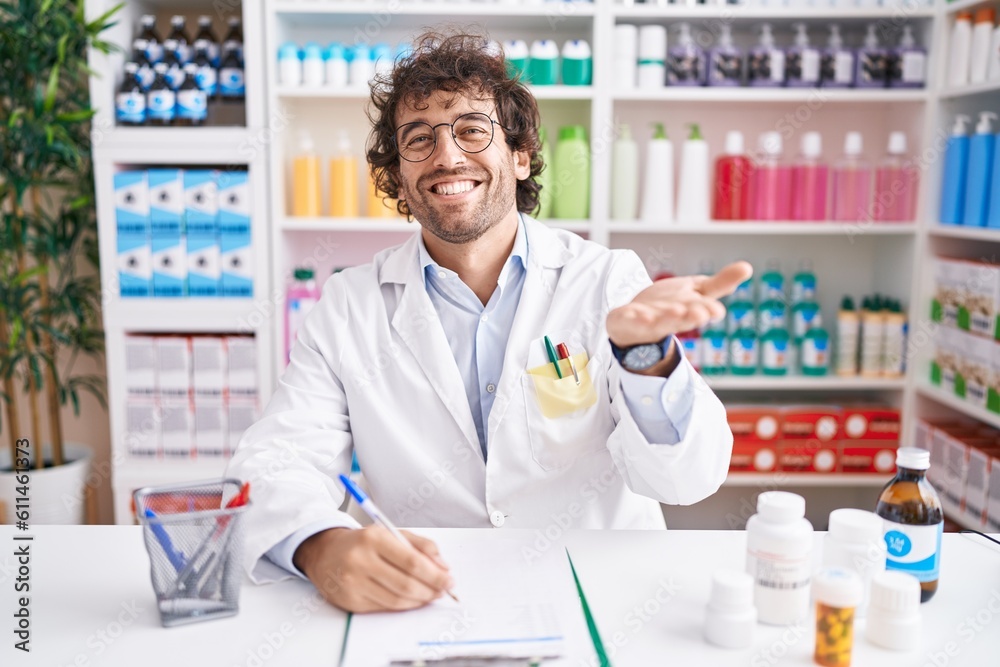 Hispanic young man working at pharmacy drugstore pointing aside with hands open palms showing copy space, presenting advertisement smiling excited happy