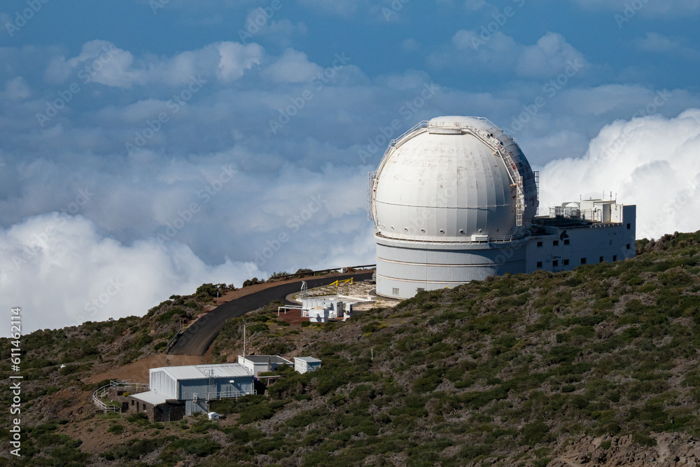 Large telescope at summit of mountain above the clouds 