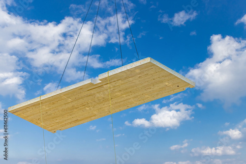 A crane hoisting a pre fabricated laminated floor panel of a mass timber multi story green, sustainable, residential high rise apartment or office building construction project
