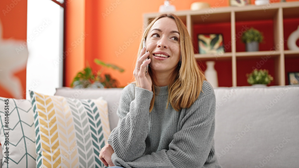 Young blonde woman talking on smartphone sitting on sofa at home Young blonde woman talking on smartphone sitting on sofa at home