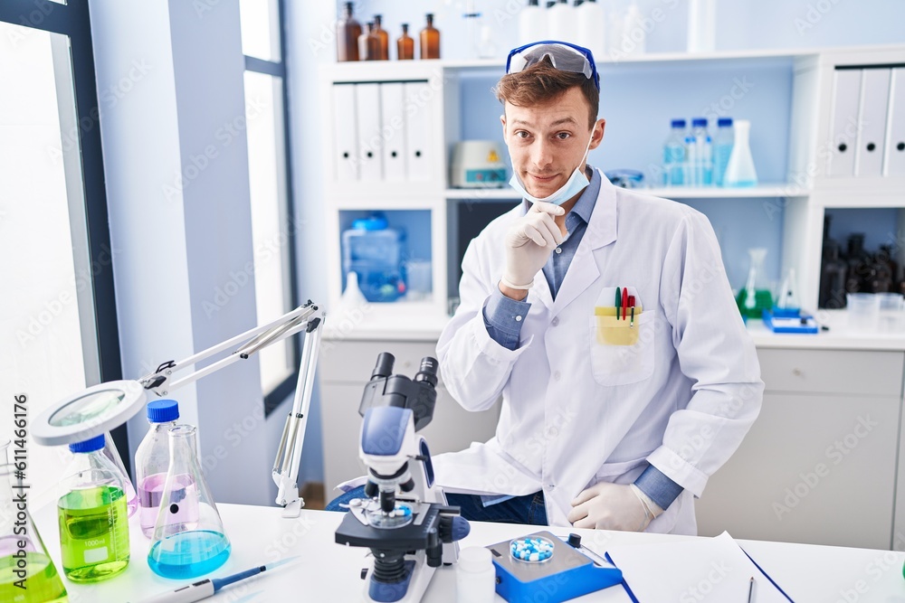 Caucasian man working at scientist laboratory smiling looking confident at the camera with crossed arms and hand on chin. thinking positive.