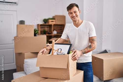 Caucasian man holding screwdriver at new home looking positive and happy standing and smiling with a confident smile showing teeth