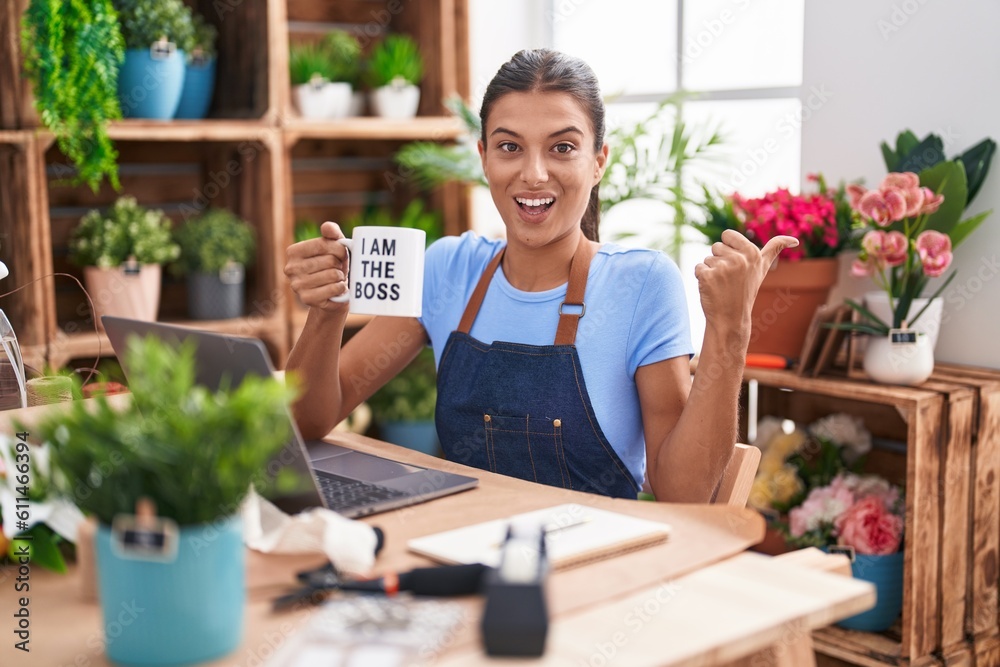 Brunette young woman working at florist shop holding i am the boss cup pointing thumb up to the side smiling happy with open mouth Brunette young woman working at florist shop holding i am the boss cup pointing thumb up to the side smiling happy with open mouth