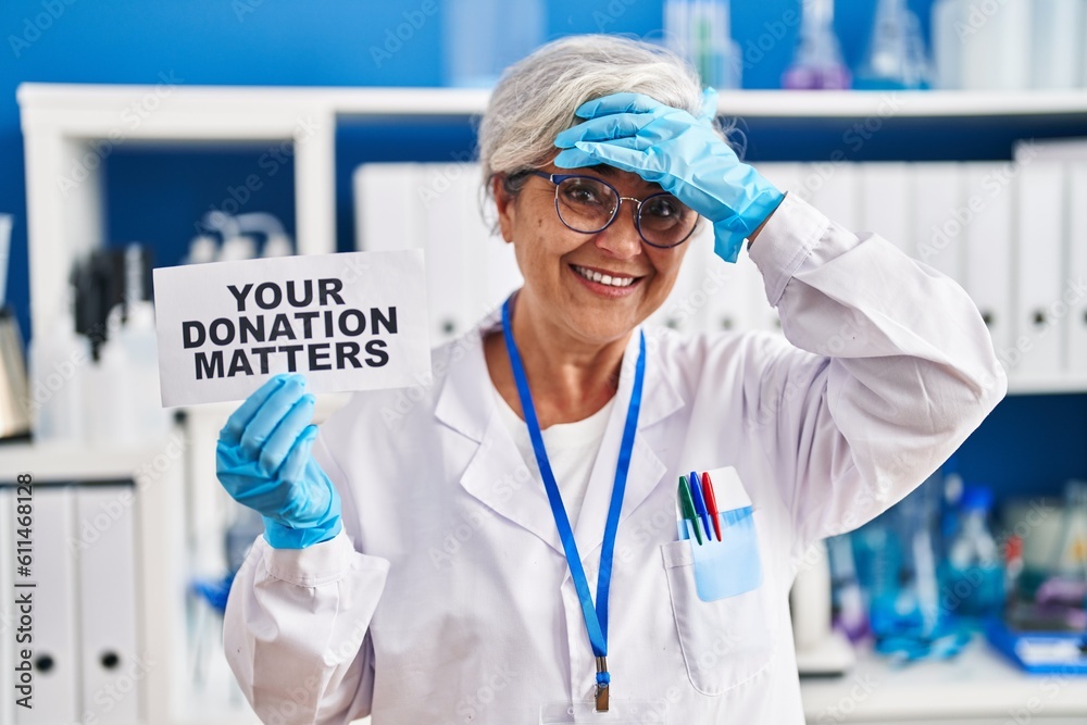 Middle age woman with grey hair working at scientist laboratory holding your donation matters banner stressed and frustrated with hand on head, surprised and angry face Middle age woman with grey hair working at scientist laboratory holding your donation matters banner stressed and frustrated with hand on head, surprised and angry face