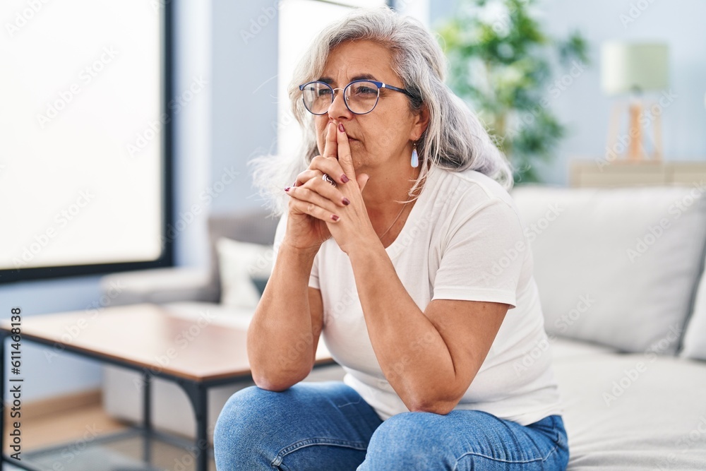 Middle age woman stressed sitting on sofa at home Middle age woman stressed sitting on sofa at home