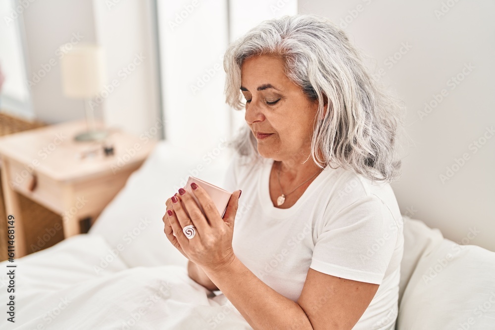 Middle age woman drinking coffee sitting on bed at bedroom Middle age woman drinking coffee sitting on bed at bedroom