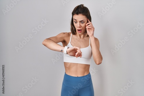 Hispanic woman wearing sportswear over isolated background looking at the watch time worried, afraid of getting late © Krakenimages.com