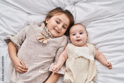 Brother and sister smiling confident lying together on bed at bedroom