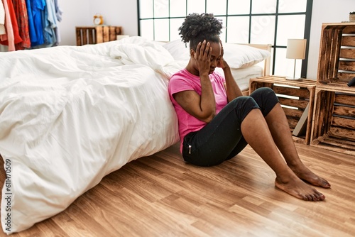 African american woman stressed sitting on floor at bedroom