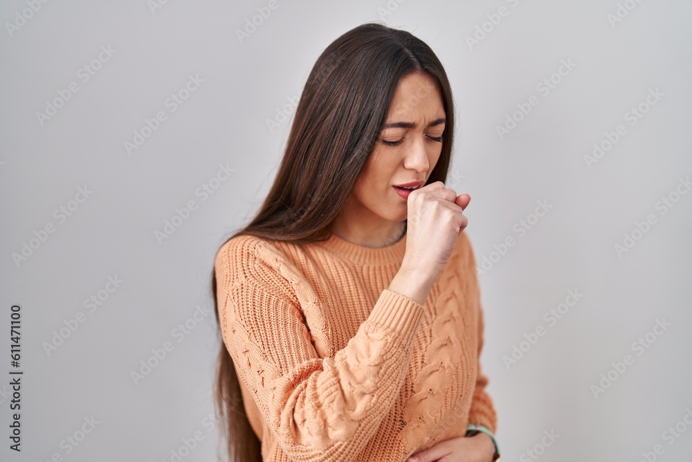 Young brunette woman standing over white background feeling unwell and coughing as symptom for cold or bronchitis. health care concept. Young brunette woman standing over white background feeling unwell and coughing as symptom for cold or bronchitis. health care concept.