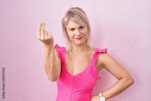 Young caucasian woman standing over pink background doing italian gesture with hand and fingers confident expression © Krakenimages.com