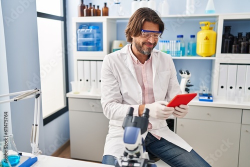 Middle age man scientist smiling confident using touchpad at laboratory