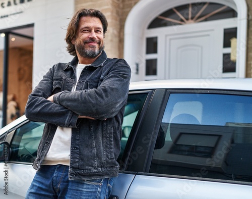 Quadro su tela Middle age man standing with arms crossed gesture leaning on car at street