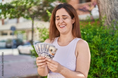 Young woman smiling confident counting dollars at park