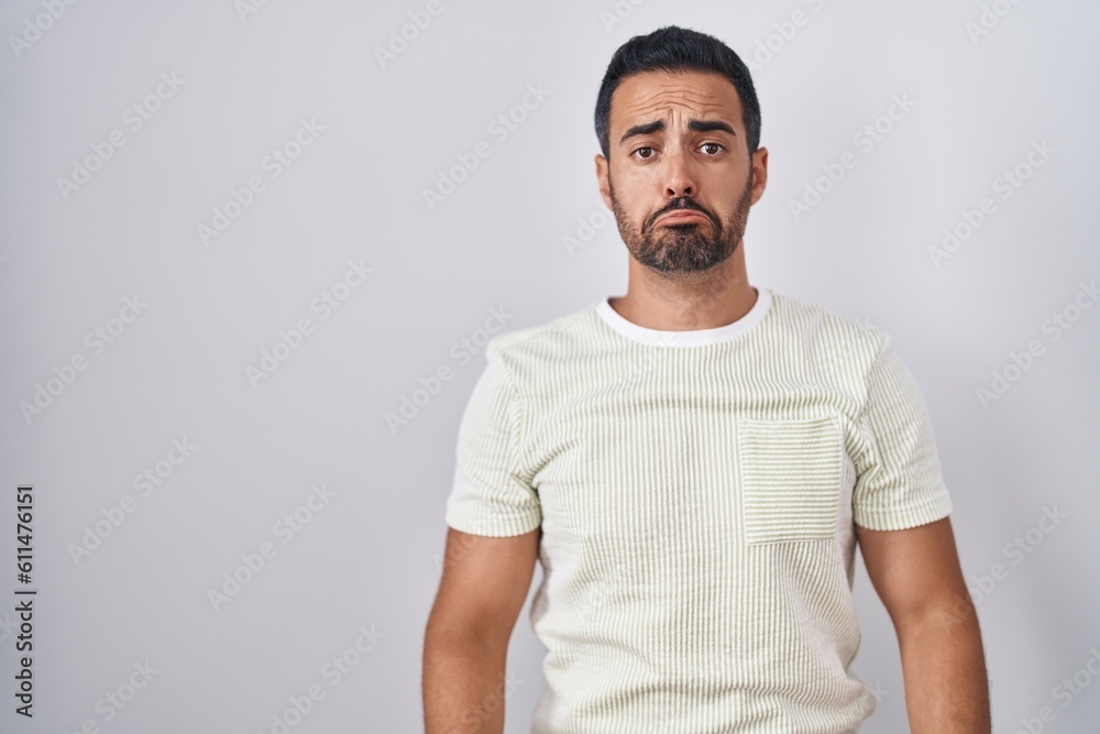 Hispanic man with beard standing over isolated background depressed and worry for distress, crying angry and afraid. sad expression. Hispanic man with beard standing over isolated background depressed and worry for distress, crying angry and afraid. sad expression.