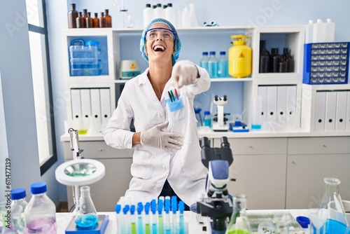 Brunette woman working at scientist laboratory laughing at you  pointing finger to the camera with hand over body  shame expression