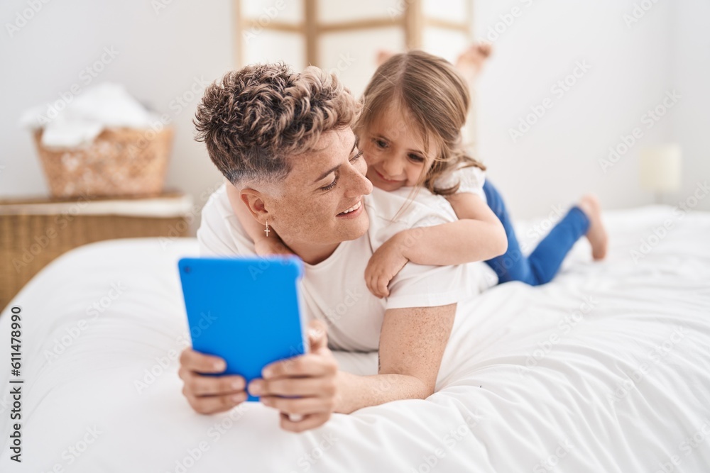 Father and daughter father and daughter using touchpad lying on bed at bedroom Father and daughter father and daughter using touchpad lying on bed at bedroom