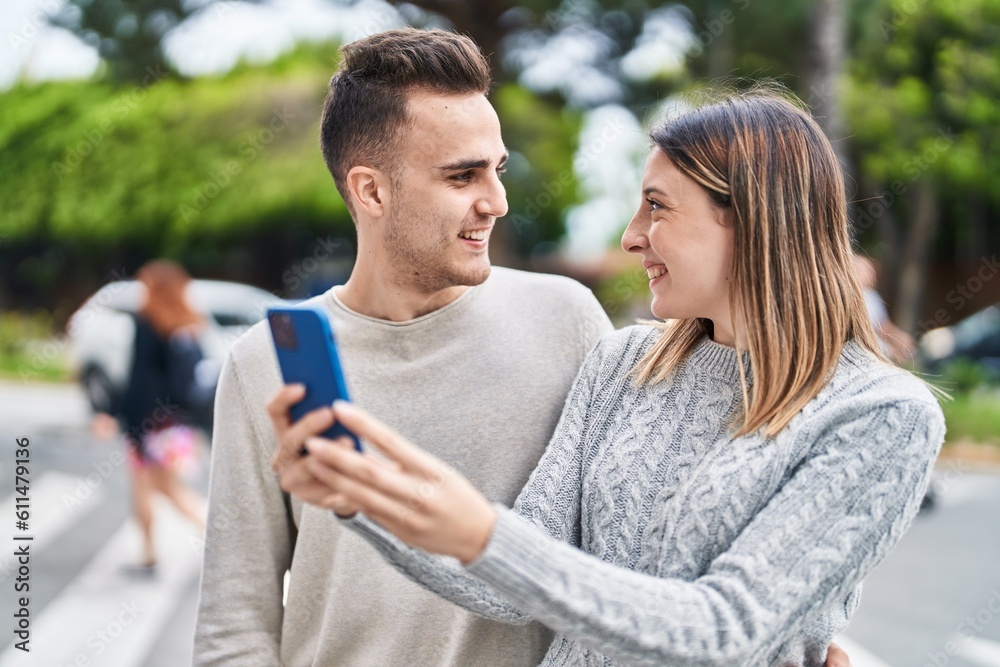 Man and woman couple hugging each other using smartphone at street Man and woman couple hugging each other using smartphone at street