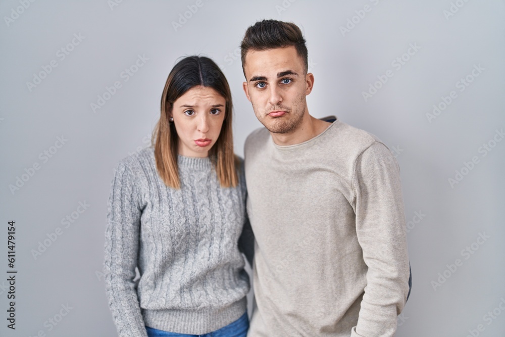 Young hispanic couple standing over white background depressed and worry for distress, crying angry and afraid. sad expression. Young hispanic couple standing over white background depressed and worry for distress, crying angry and afraid. sad expression.