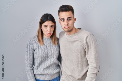 Young hispanic couple standing over white background depressed and worry for distress, crying angry and afraid. sad expression.