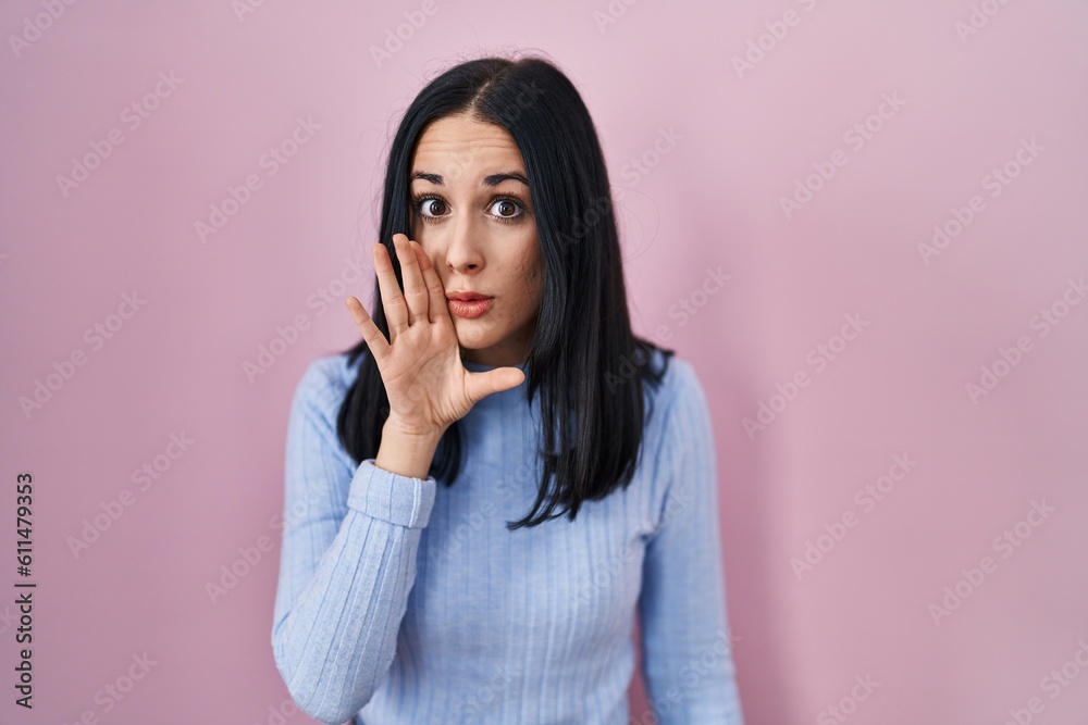 Hispanic woman standing over pink background hand on mouth telling secret rumor, whispering malicious talk conversation Hispanic woman standing over pink background hand on mouth telling secret rumor, whispering malicious talk conversation