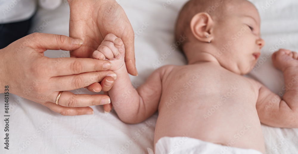 Adorable caucasian baby lying on bed having hand massage at bedroom Adorable caucasian baby lying on bed having hand massage at bedroom