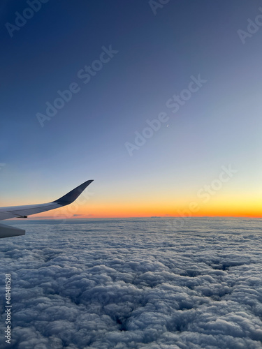 Airplane flying over the clouds during sunset