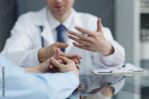 A close photo of the hands of a female patient who is gesturing near a doctor during an appointment in a hospital.