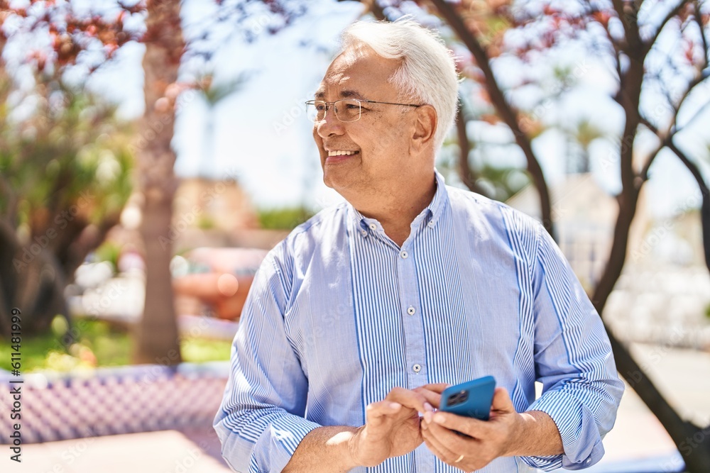 Fototapeta premium Senior man smiling confident using smartphone at park